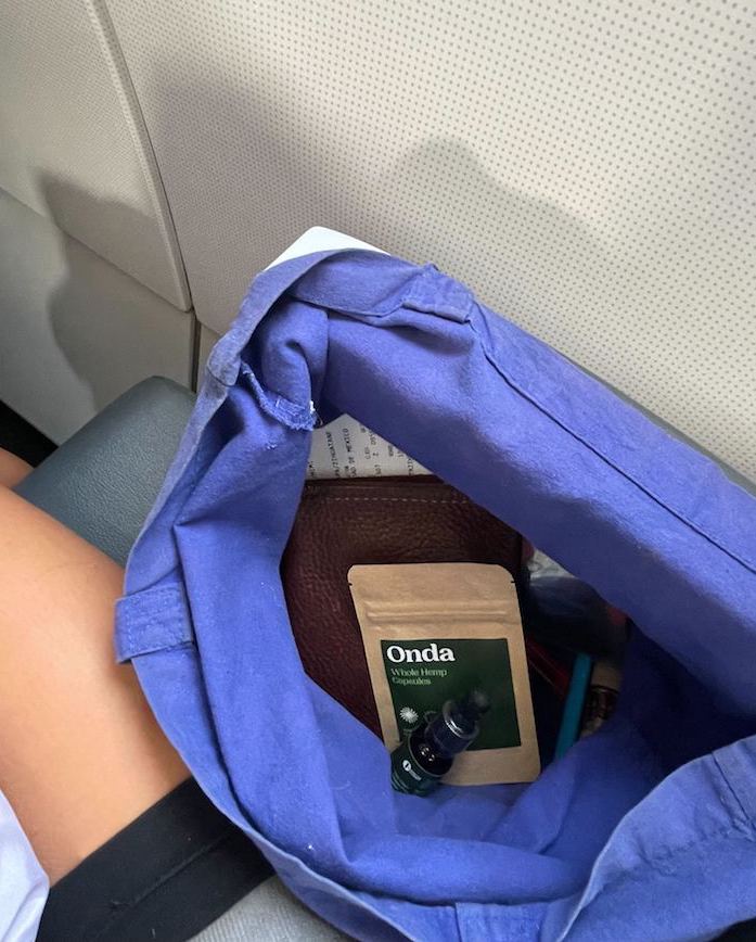 woman traveling in plane with purple backpack - cbd for travel anxiety